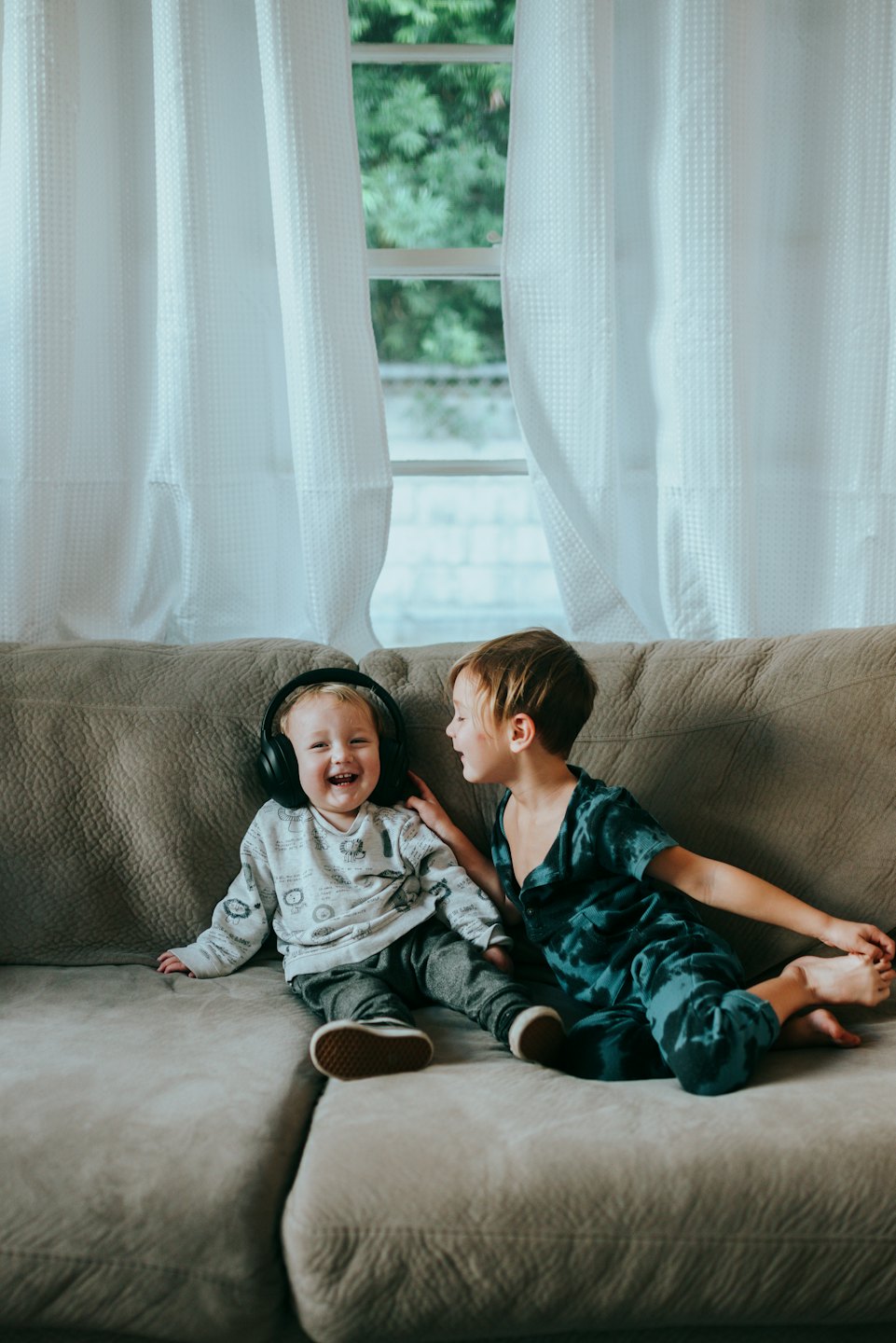 Due bambini seduti sul divano e che ridono insieme.
