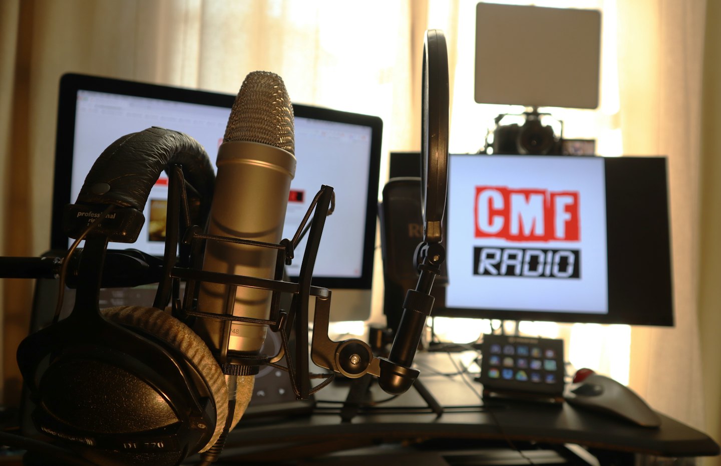 Microfono da podcasting con filtro anti-pop e cuffie su una scrivania.