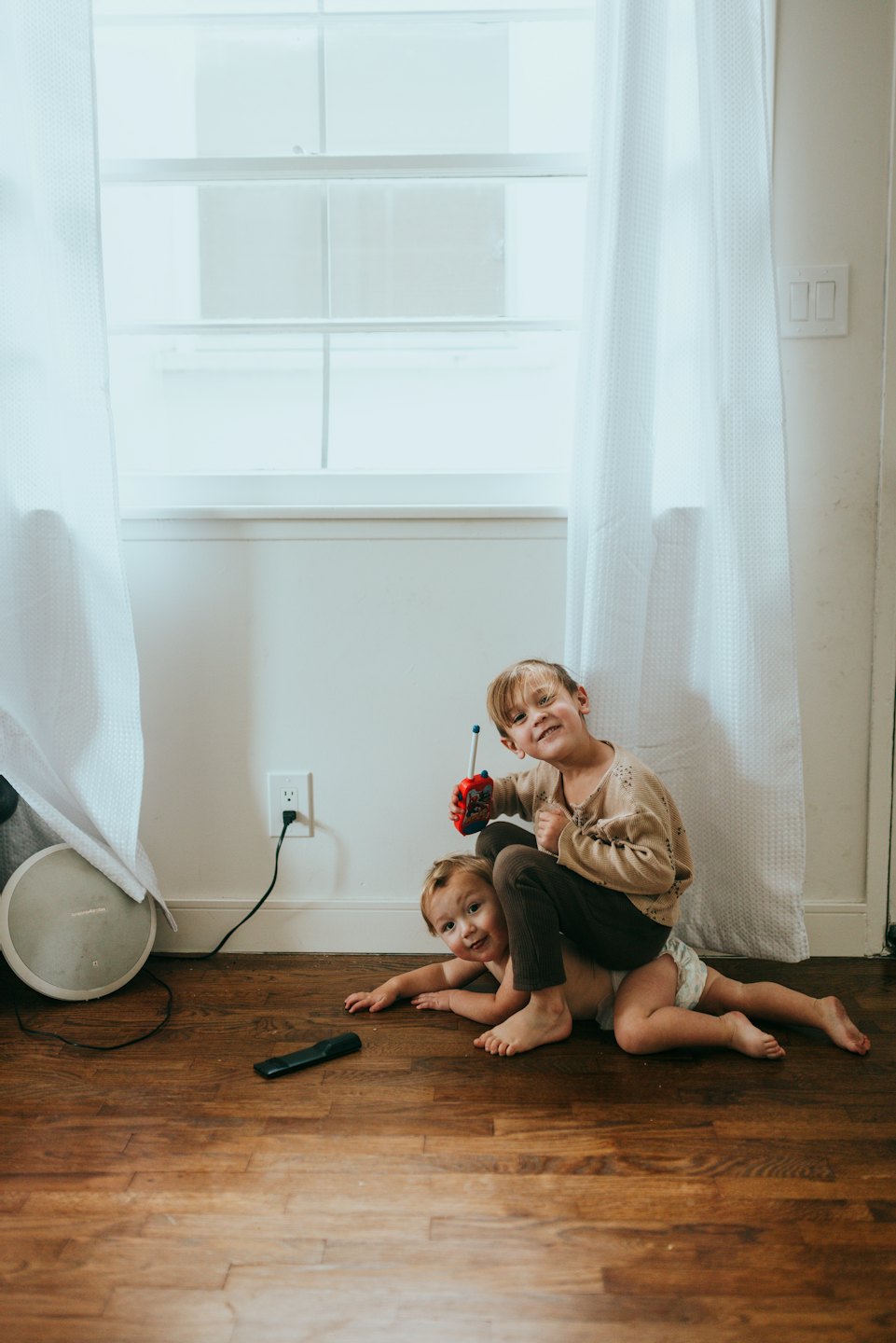 Due bambini giocano in casa con un walkie-talkie giocattolo.